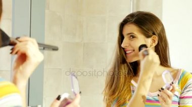 Sevimli genç kadın kamera seyir makyaj uygulamak ayna önünde