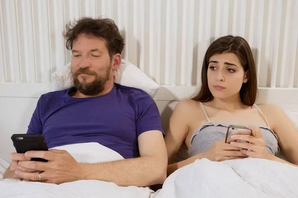 Woman jealous in bed checking phone of boyfriend — Stock Photo, Image