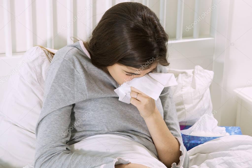 Sick woman sneezing strong ill sitting in bed