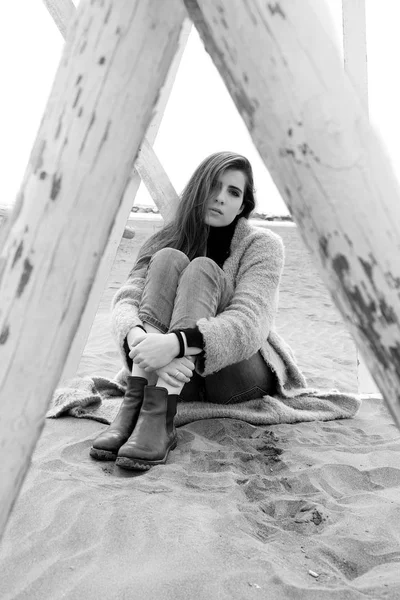 Triste femme assise sur la plage se sentant perdue et seule regardant caméra noir et blanc — Photo