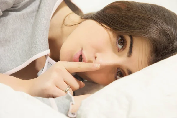 Молодая женщина в постели делает знак молчания — стоковое фото