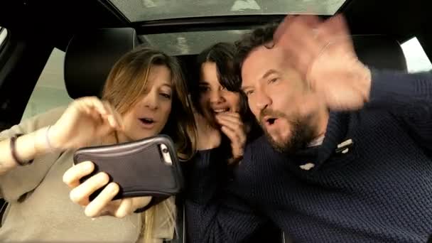 Hombre y mujeres sentados en el coche haciendo una videollamada con amigos — Vídeos de Stock