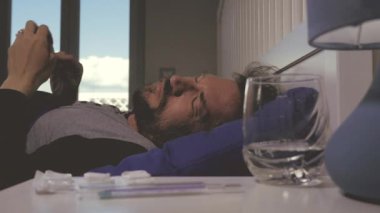 Çok şiddetli baş ağrısı ve ateşi olan hasta bir adam yatakta.