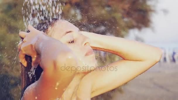 Linda mujer joven lavando el cabello bajo la ducha en la luz exterior fugas cámara lenta — Vídeos de Stock