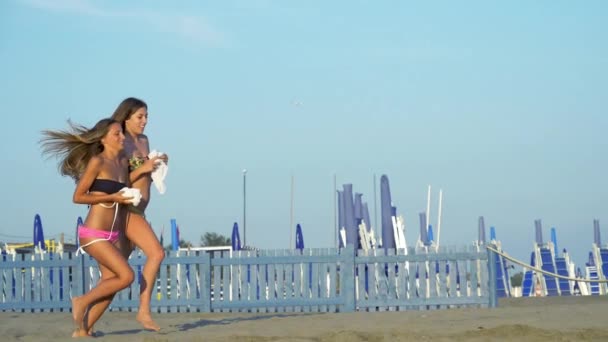 Glada tonåringar-modeller som kör på stranden mot havet slow motion — Stockvideo