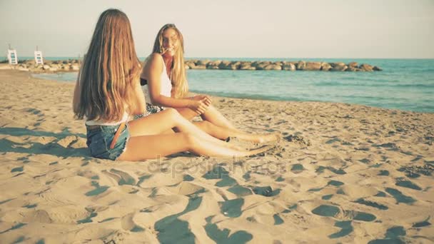 Mooie blonde meisjes met lang haar zittend op het strand glimlachend slowmotion analoge retro-stijl — Stockvideo