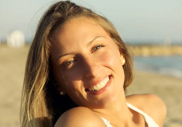 Primo piano di bella giovane donna bionda con gli occhi azzurri sorridenti sulla spiaggia — Foto Stock