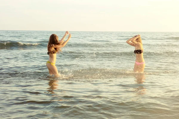 Meninas bonitas em biquíni jogando água espirrando no oceano — Fotografia de Stock