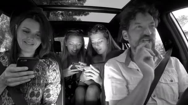 Man desperate about family not listening to him playing with cell phone in car black and white — Stock Video