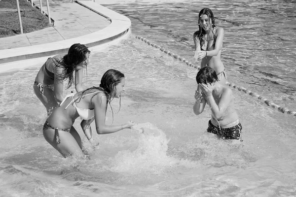 Três meninas salpicando menino com armas de água na piscina preto e branco — Fotografia de Stock