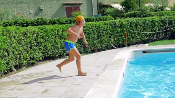Süßer Junge macht lustiges Gesicht beim Sprung in Pool-Zeitlupe — Stockvideo
