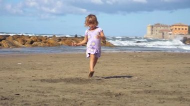 Koşma ve atlama beach süper ağır çekim üzerinde sevimli küçük kız