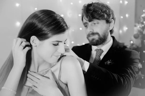 Eleganter Mann legt Halskette Geschenk an Freundin Weihnachtsnacht schwarz-weiß romantisch — Stockfoto