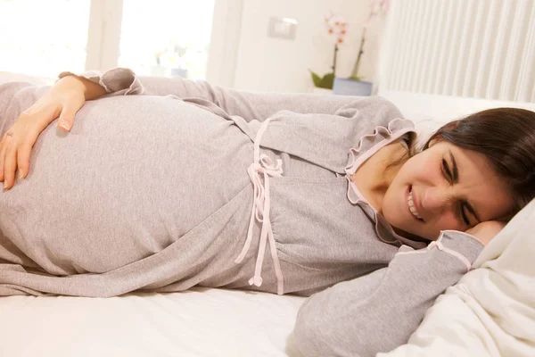 Pregnant woman lying in bed feeling pain — Stock Photo, Image