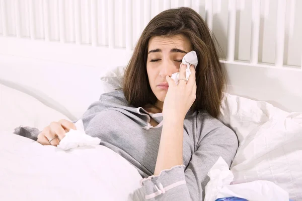 Mujer enferma en la cama sosteniendo el pañuelo — Foto de Stock
