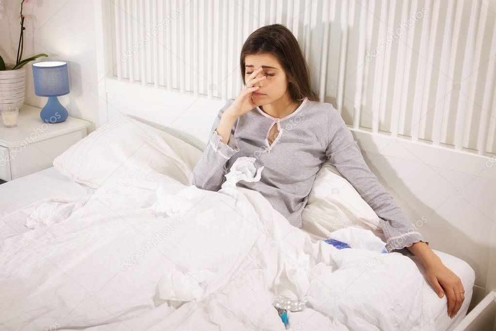 Ill woman in bed holding handkerchief feeling headache