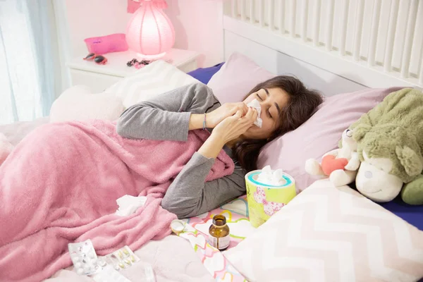 Enferma hispana adolescente en la cama estornudando — Foto de Stock