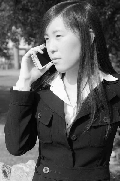 Serious asian business woman  talking on the phone in park black and white — Stock Photo, Image