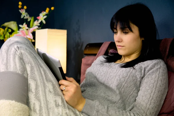 Милая женщина сидит в постели расслабляющий взгляд социальной сети на планшете — стоковое фото