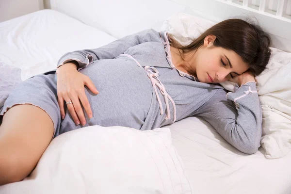 Беременная женщина мирно спит в постели — стоковое фото