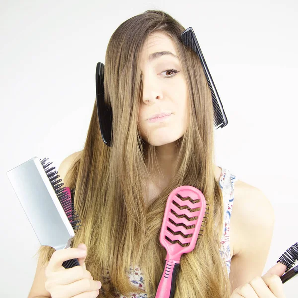 Mulher fazendo expressão muito engraçada com pentes e escovas em seu cabelo longo — Fotografia de Stock