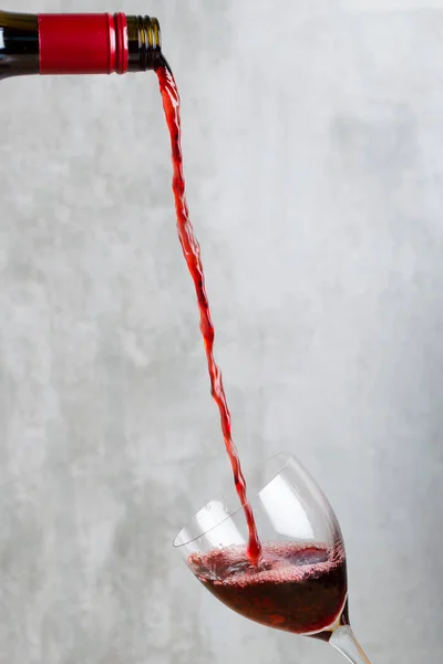 병에 담긴 붉은 포도주를 유리잔에 붓는 모습 — 스톡 사진