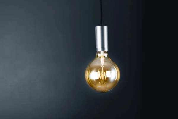 Lightbulb hanging in a dark room — Stock Photo, Image