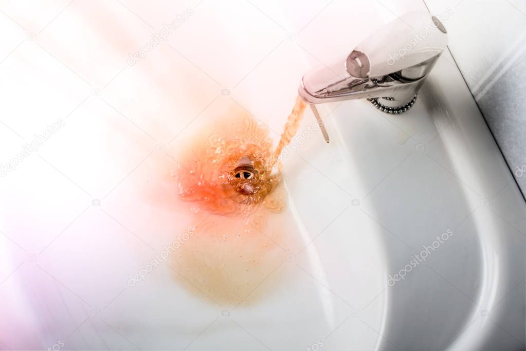 Dirty brown water running into a sink