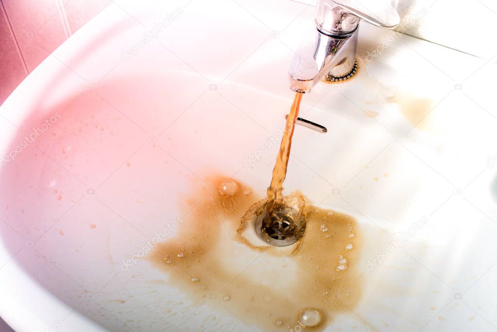 Dirty brown water running into a sink