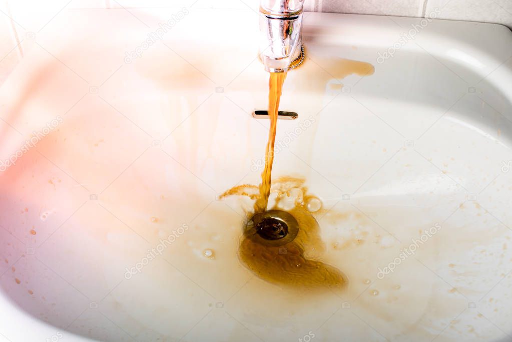 Dirty brown water running into a sink