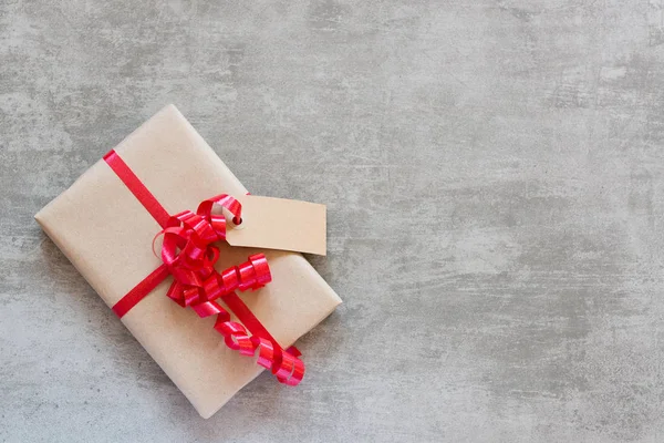 Gift with red ribbon and tag on a concrete table — Stock Photo, Image