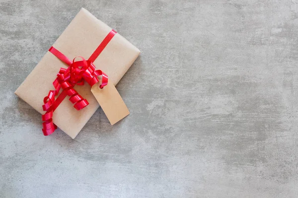 Gift with red ribbon and tag on a concrete table — Stock Photo, Image
