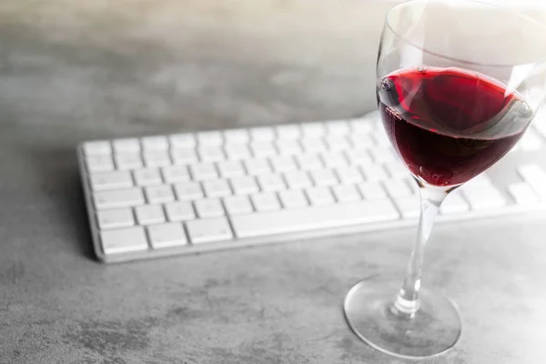 Красное вино и компьютерная клавиатура на бетонном столе с акцентом на т — стоковое фото