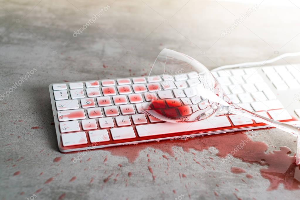 Red wine spilled over computer keyboard on concrete table