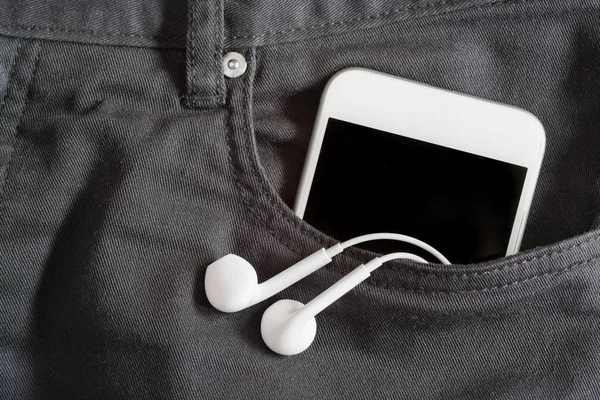 Primo piano di smartphone e auricolare nella tasca anteriore sui pantaloni — Foto Stock