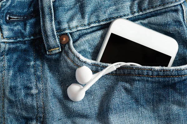 Close up de smartphone e fone de ouvido no bolso frontal nas calças — Fotografia de Stock