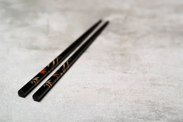 Black chopsticks on concrete background with selective focus — Stock Photo, Image