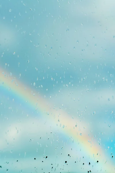 Water drops on a window with the rainbow in the background Stock Picture