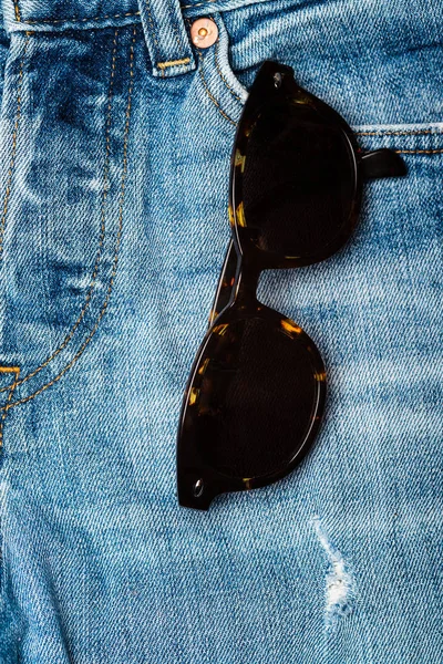 Sunglasses hanging out of front pocket on jeans — Stock Photo, Image