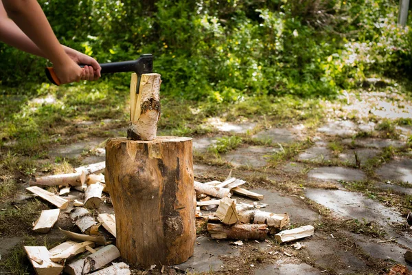 Jonge man met bijl hout hakken op een hakblok — Stockfoto