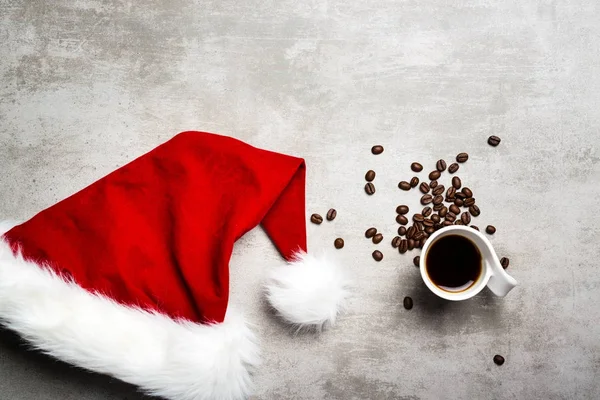 Red santa hat and a cup of coffee on a concrete table — Stock Photo, Image