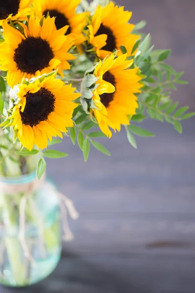 Bouquet of bright sunflowers in a glass jar on a wooden table. — Stock Photo, Image