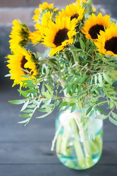 Bouquet of bright sunflowers in a glass jar on a wooden table. — Stock Photo, Image