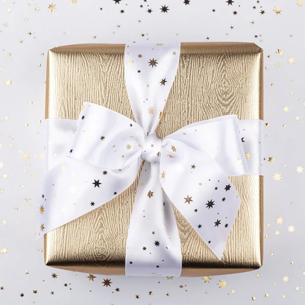 Gold gift box with a white ribbon. — Stock Photo, Image