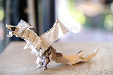 kahverengi bir masa üstünde katlanmış gazeteden yapılmış bir model origami ejderha