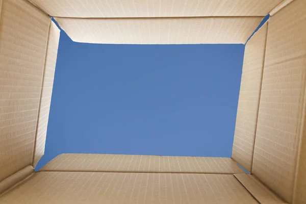 Pohled z lepenkové krabice. Modrá obloha venku. — Stock fotografie