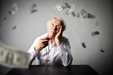 Yaşlı adam ile tespih dua ediyor. Düşen Doları banknot.