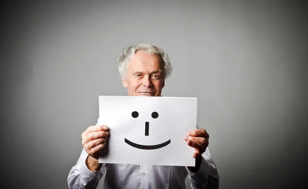 Velho homem de branco está segurando papel branco com sorriso . — Fotografia de Stock