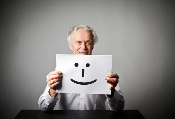 Velho homem de branco está segurando papel branco com sorriso . — Fotografia de Stock