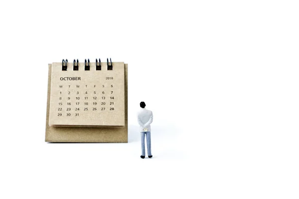 В октябре. Календарь и миниатюрный пластиковый человек на белом фоне — стоковое фото